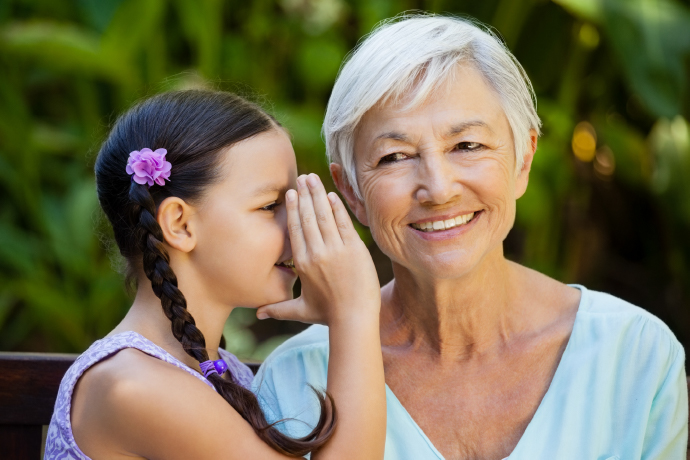 A child speaking in an older person's ear